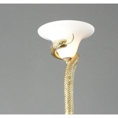 a white lamp with a gold snake on it's side and a gray background