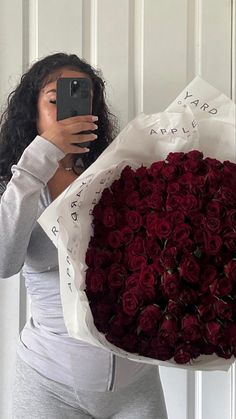 a woman taking a selfie while holding a large bouquet of roses in front of her face