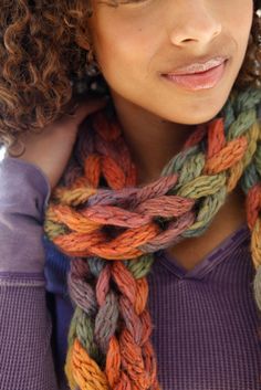 a woman with curly hair wearing a multicolored knitted scarf over her shoulder