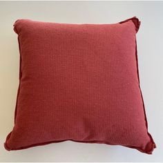 a red pillow sitting on top of a white wall