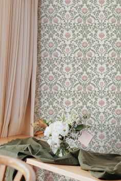 a vase filled with flowers sitting on top of a wooden table next to a window