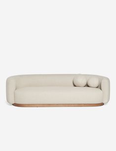 a white couch with three pillows on it's back and two balls in the middle