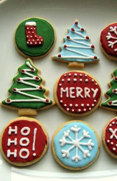 decorated cookies on a white plate with merry words and christmas tree decorations in the middle