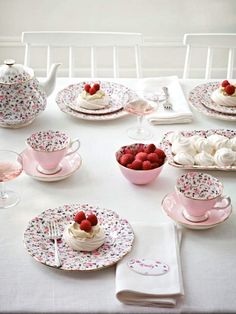 a pink table topped with plates and cups filled with desserts on top of it