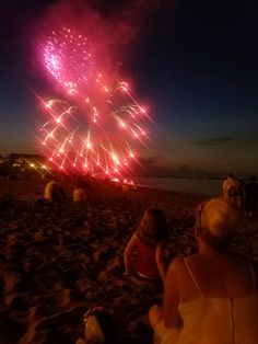 people watching fireworks on the beach at night