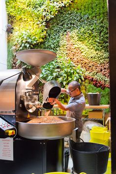 a man standing in front of a machine making something out of some kind of pot