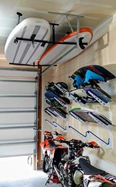 there are many snowboards and skis on the rack in this garage, along with two mopeds