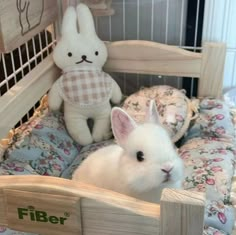 a small white rabbit sitting in a wooden bed with flowers on it's cover