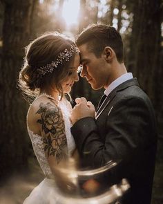 a bride and groom standing together in the woods during their wedding photo session at sunset