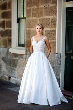 a woman standing in front of a building wearing a wedding dress