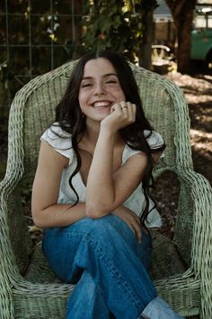 a woman sitting in a wicker chair smiling