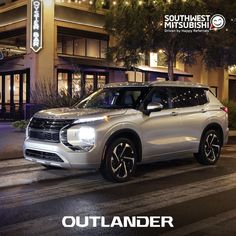 a white suv parked in front of a building at night with the words outlander written on it