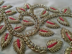 a close up view of a gold and red beaded design on a white cloth