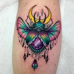 a colorful tattoo on the leg of a woman with an insect and moon in it