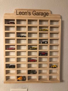 a wooden shelf with cars on it and the words leon's garage above it