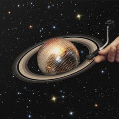 a hand holding a brush in front of a disco ball with stars on the background