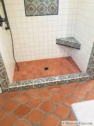 a bathroom with tiled flooring and tile shower stall in the corner, next to a bench