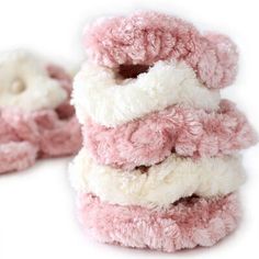 several pink and white fuzzy slippers stacked on top of each other in front of a white background