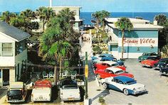 cars are parked on the street in front of buildings with palm trees and ocean view