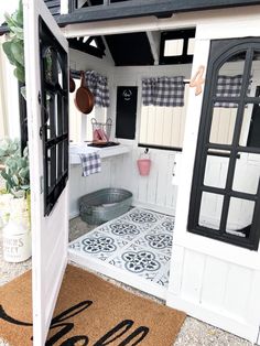 the inside of a tiny house with an open door and potted plants in it