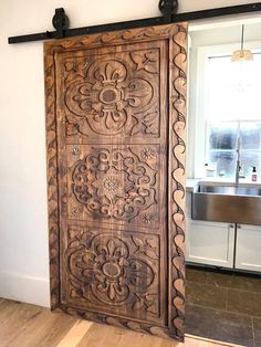 an old wooden door in the corner of a room with a sink and window behind it