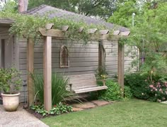 a wooden bench sitting in the middle of a garden next to a house with flowers