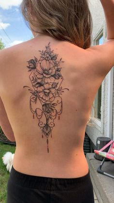 the back of a woman's body with flowers and leaves tattooed on her lower back