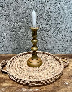 a candle is sitting on top of a wicker basket with a rope around it