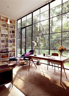 a living room filled with lots of windows and furniture next to a book shelf full of books