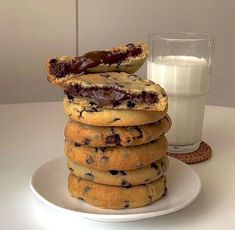 a stack of cookies sitting on top of a white plate next to a glass of milk