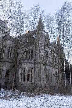 an old stone building surrounded by trees and snow