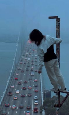 a person on a skateboard doing tricks in the air over a busy highway and bridge