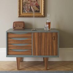 a painting on the wall next to a wooden cabinet with drawers and an old radio