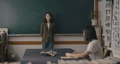 two women sitting at a table in front of a blackboard