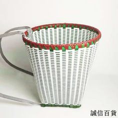 a white wicker basket with red and green trimmings on the bottom, attached to a gray strap