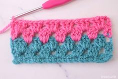 the crochet stitch is being worked on by a pink and blue yarn needle