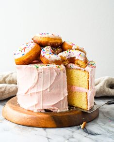 a cake with pink frosting and sprinkles is on a wooden platter