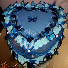 a heart shaped cake with blue butterflies on it's edges and frosting in the shape of a heart