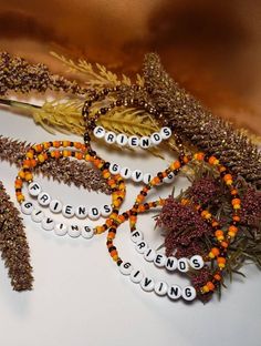 several bracelets with words written on them sitting next to some dried plants and leaves