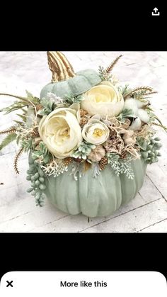 a green pumpkin filled with white flowers and greenery