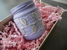 a purple mason jar sitting on top of pink shredded paper next to a wooden box