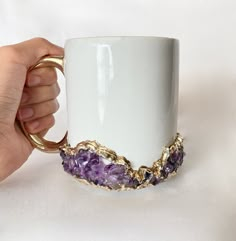 a hand holding a coffee mug with gold trimmings and amethorate