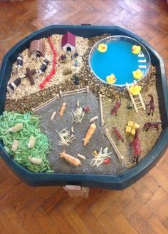 a table that has some toys in it on top of wood flooring and a blue tray