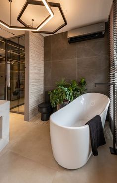 a large white bath tub sitting inside of a bathroom next to a plant filled wall