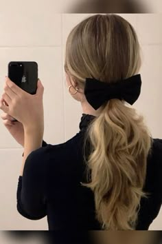 a woman taking a selfie in front of a mirror wearing a black bow tie