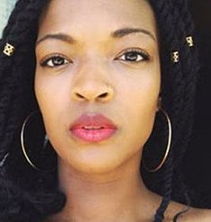 a woman with large hoop earrings on her head looking at the camera while wearing an earring