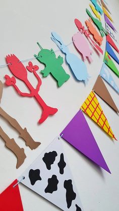 paper cut out animals and cows are hanging on a string from a table with flags