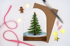 a card with a christmas tree in a snow globe surrounded by craft supplies and scissors