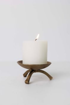 a small white candle sitting on top of a wooden stand with a metal holder underneath it