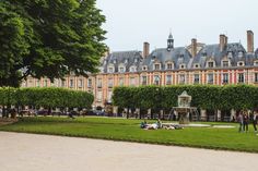 people are sitting on the grass in front of a building with many windows and trees